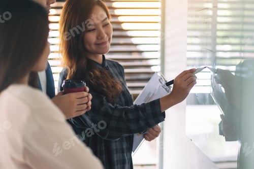 Preview: Group of business people looking and discussing ideas over whiteboard in office