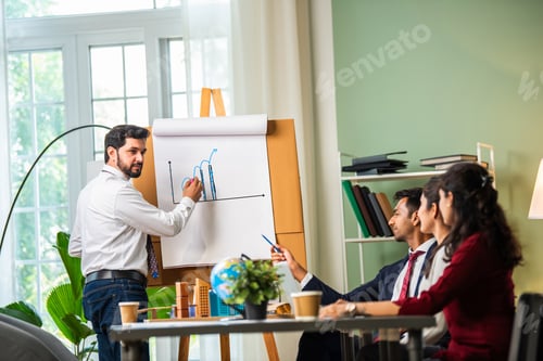 Preview: Group Of Businesspeople Looking At Young Indian asian Businessman giving presentation on white board