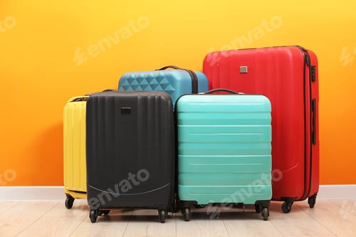 Preview: Many colorful suitcases on floor near orange wall