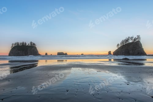 Preview: Sunrise horizon behind rock formations on beach