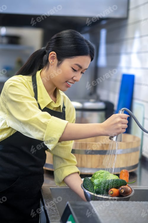Preview: Woman in the kitchen washing vegetables before cooking