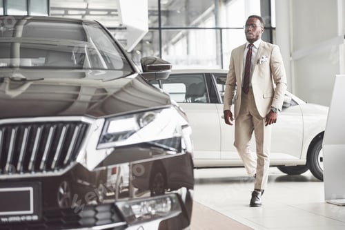 Preview: Young black businessman on auto salon background. Car sale and rent concept