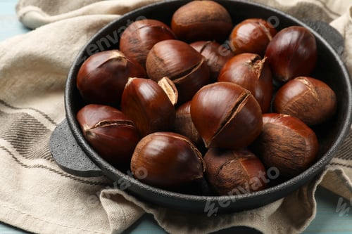 Preview: Fresh edible sweet chestnuts in frying pan on table, closeup