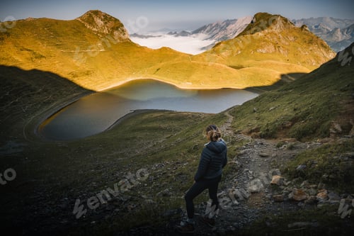 Preview: Hiker contemplating lac de montagnon in the french pyrenees at sunrise