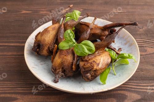 Preview: Smoked quails on a ceramic plate on a brown wooden background. Side view, close up