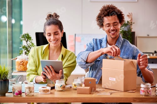Preview: Young Couple Running Online Business From Home Packing Boutique Candles Ready For Shipping