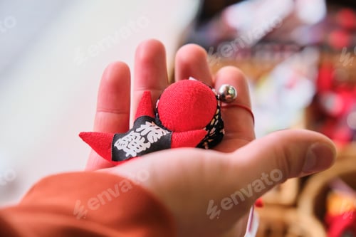Preview: Hand holding a Sarubobo doll in a shop. Japanese amulet. Takayama, Gifu, Japan.