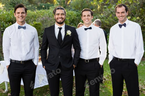 Preview: Portrait of groom and groomsmen standing with hands in pocket