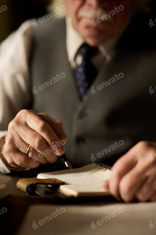 Preview: Senior Caucasian Man Writing Notes with Fountain Pen at Desk Indoors
