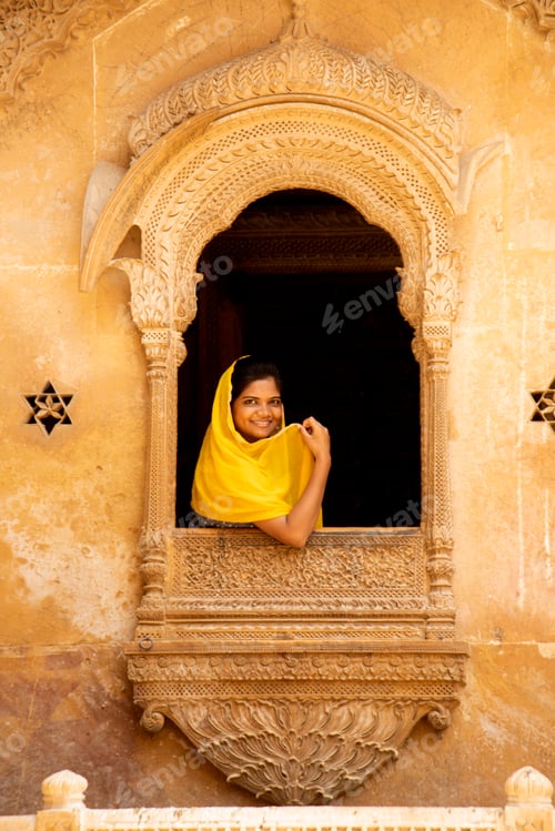 Preview: Young woman tourist in stone carved window, India.
