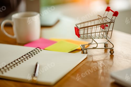 Preview: Laptop,note book,Note and small shopping cart on table. Internet shopping concept