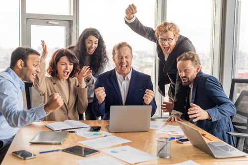 Preview: Excited Business Team Celebrating Success Around Conference Table in Office