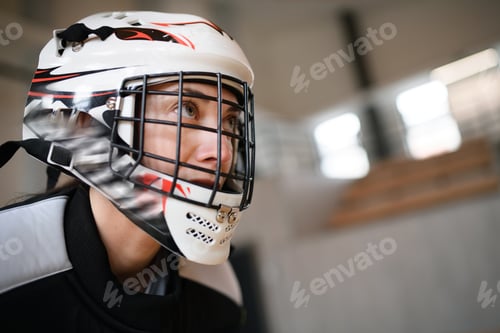 Preview: Close-up of woman floorball goalkeeper in helmet concetrating on game in gym.
