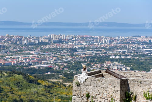 Preview: Amazing view of a woman in a white dress on a fortress wall overlooking the city of Split, Croatia