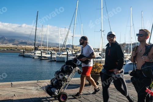 Preview: Divers walking in marina with scuba tanks on sunny day