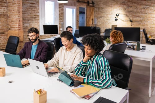 Preview: Multi ethnic team collaborating on project in modern office