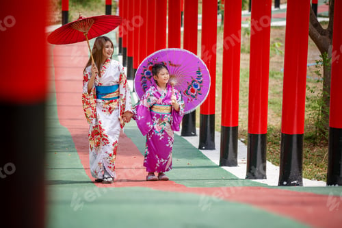 Preview: Colorful kimono walk through a vibrant pathway with red columns and traditional umbrellas