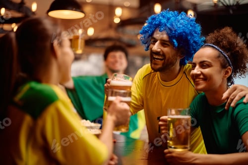 Preview: Happy sports fans toasting with beer in a pub.