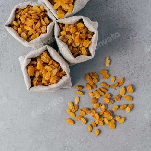 Preview: Golden raisins from dried grapes in burlap textile sacks photographed from above