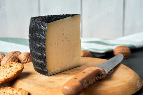 Preview: Semi-cured cheese wedge on wooden board with walnuts