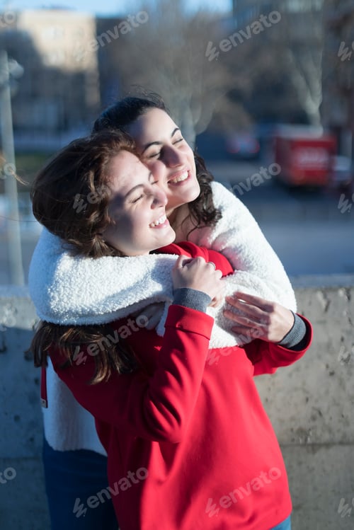 Preview: Joyful hug between two friends outdoors