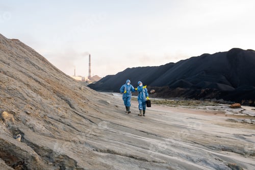 Preview: Two ecologists in protective workwear moving along hill while investigating dangerous territory