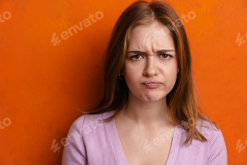 Preview: Young ginger displeased woman frowning and looking at camera