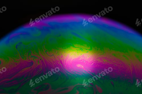 Preview: Rainbow soap bubble on a black background. Close-up of a colorful surface.
