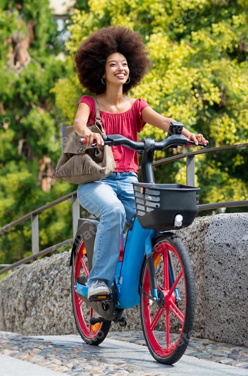 Preview: Delighted ethnic female riding bicycle on street in summer