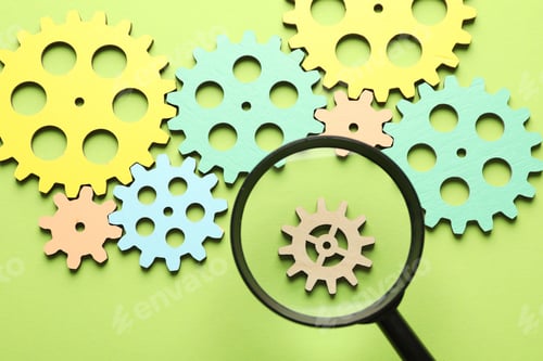 Preview: Unemployment. Gearwheels and magnifying glass on green background, flat lay