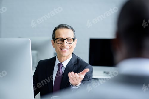 Preview: selective focus of smiling businessman talking to colleague while working in office
