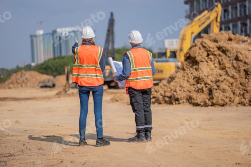 Preview: Construction surveyor or engineer working construction site blueprint and laptop for inspection deta