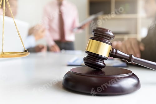 Preview: Wooden gavel on table in lawyer's office. Lawyer having team meeting with the client.