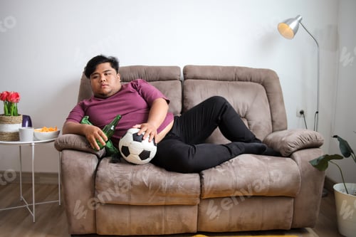 Preview: Comfy Man Lounging With Beer and Soccer Ball on Couch Indoor Chill Time Perfect