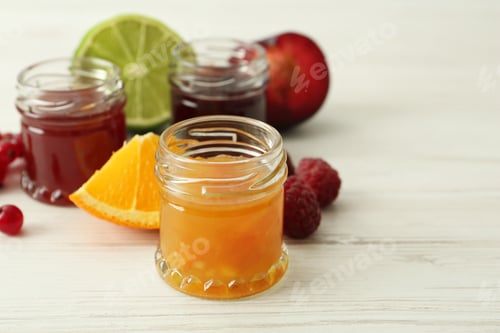 Preview: Jars of different jams and ingredients on white wooden table