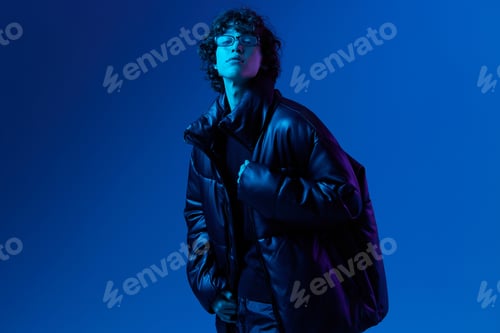 Preview: Man in winter down jacket model posing with glasses, hipster lifestyle, portrait blue background