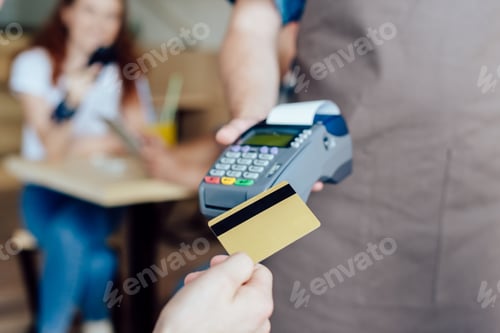 Preview: close-up partial view of person client holding credit card and waiter holding payment terminal