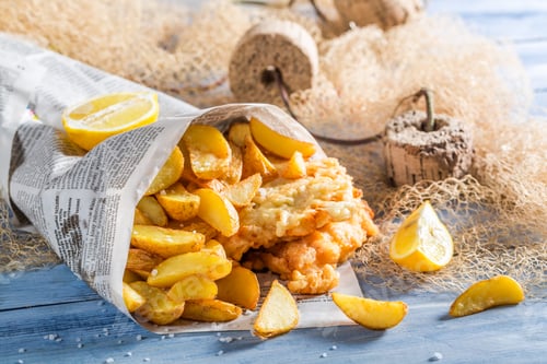 Preview: Delicious fish and chips in newspaper on old wooden table