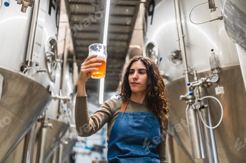 Preview: Woman brewer inspecting craft beer in brewery