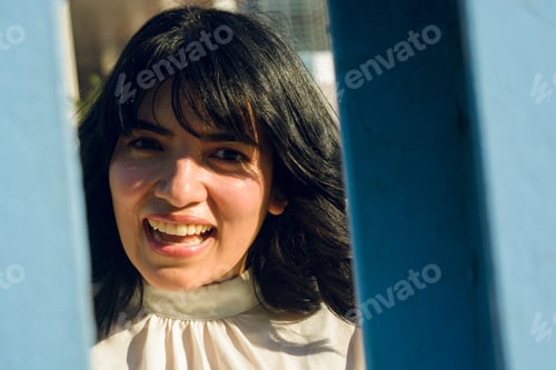Preview: close-up portrait of young venezuelan woman smiling surprised looking at the camera, copy space.