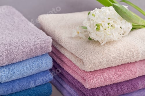 Preview: Two stacks of colorful bath towels with hyacinth flower on light background.