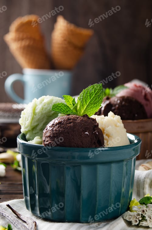 Preview: Three scoops of Vanilla pistachio and chocolate icecream balls in clay bowls on wooden kitchen table