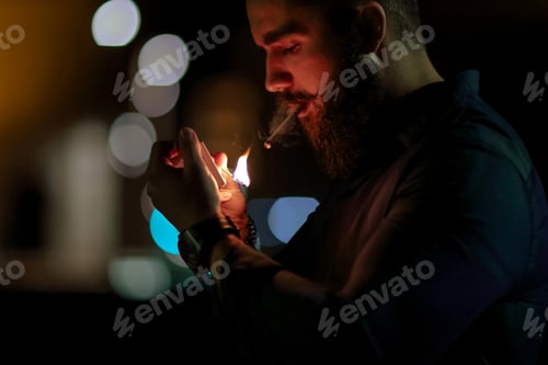 Preview: The man in the dark lights a cigarette with a match