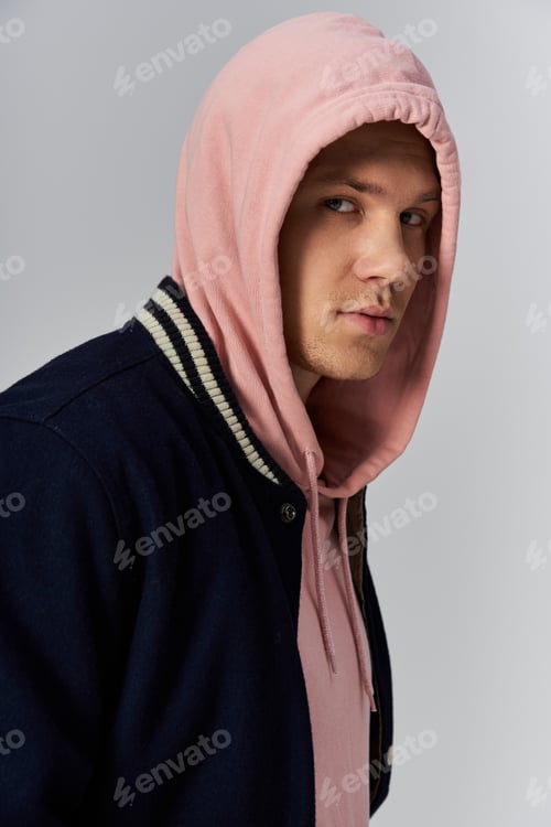Preview: Young handsome man wearing a pink hoodie and a dark jacket poses with confidence and style