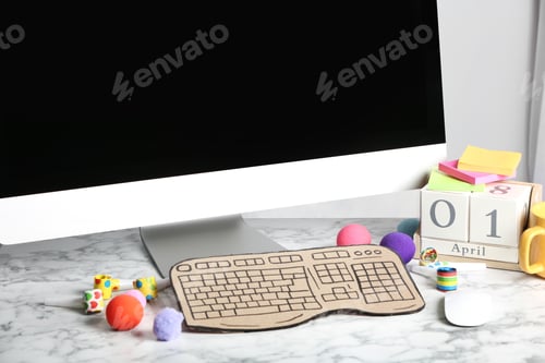 Preview: Computer with cardboard keyboard on white marble table. April Fool's Day