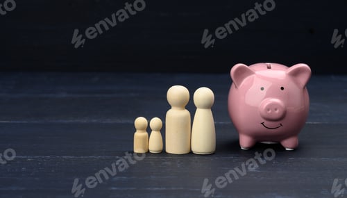 Preview: Wooden family figurines and pink ceramic piggy bank, savings concept, budget control