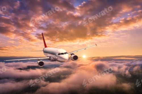 Preview: Airplane is flying above the clouds at sunset in summer