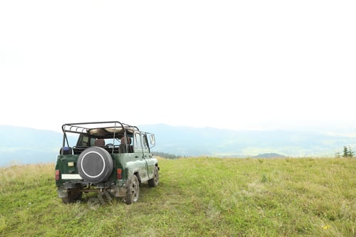 Preview: Dirty car on green hill in wilderness