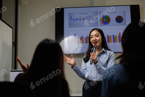 Preview: Businesswoman presenting business plan using microphone and monitor in meeting room