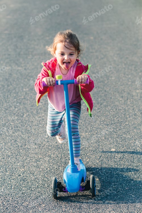 Preview: Little adorable girl having fun riding on scooter